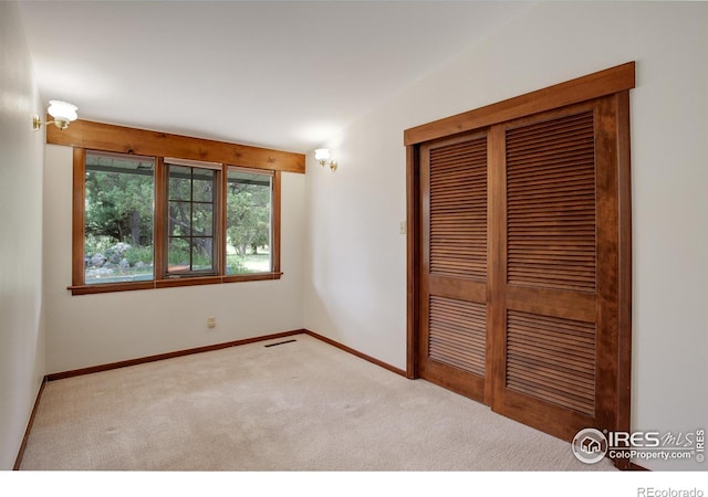 unfurnished bedroom featuring light carpet and a closet