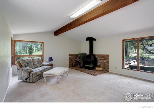 living room featuring a wood stove, plenty of natural light, vaulted ceiling with beams, and light colored carpet