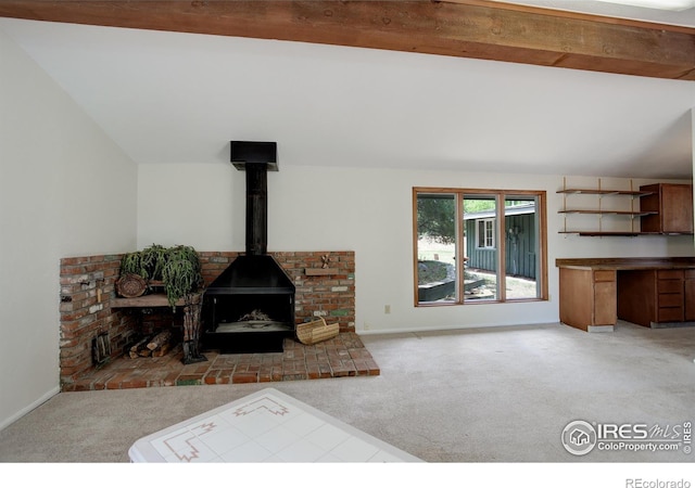 living room featuring lofted ceiling with beams, a wood stove, and light colored carpet