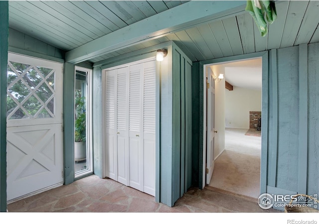 view of exterior entry featuring vaulted ceiling with beams and wooden ceiling