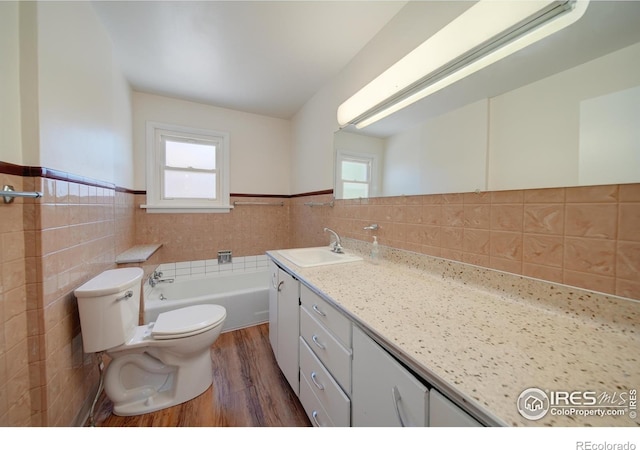 bathroom with vanity, a washtub, toilet, tile walls, and wood-type flooring