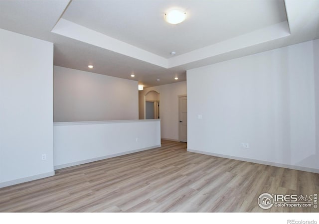 empty room with light hardwood / wood-style flooring and a tray ceiling