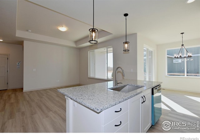 kitchen featuring white cabinets, sink, a raised ceiling, stainless steel dishwasher, and a center island with sink