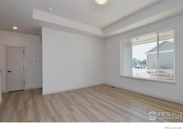 unfurnished room featuring light hardwood / wood-style flooring and a raised ceiling