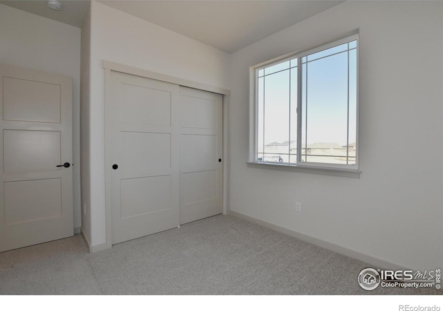 unfurnished bedroom with light carpet and a closet