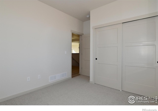 unfurnished bedroom with light carpet and a closet