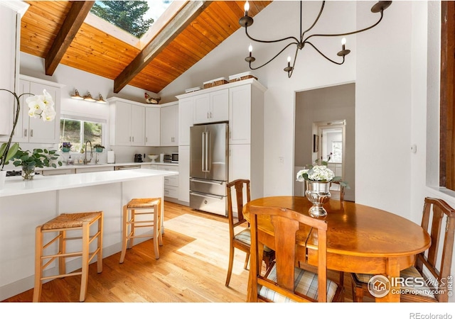 dining room with a notable chandelier, a skylight, wood ceiling, light wood finished floors, and beamed ceiling