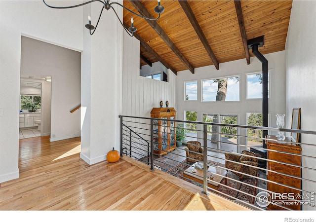 interior space with high vaulted ceiling, beam ceiling, wood ceiling, and light wood-style floors