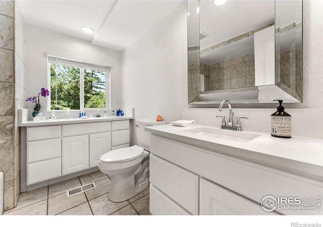 bathroom with a tile shower, vanity, and toilet