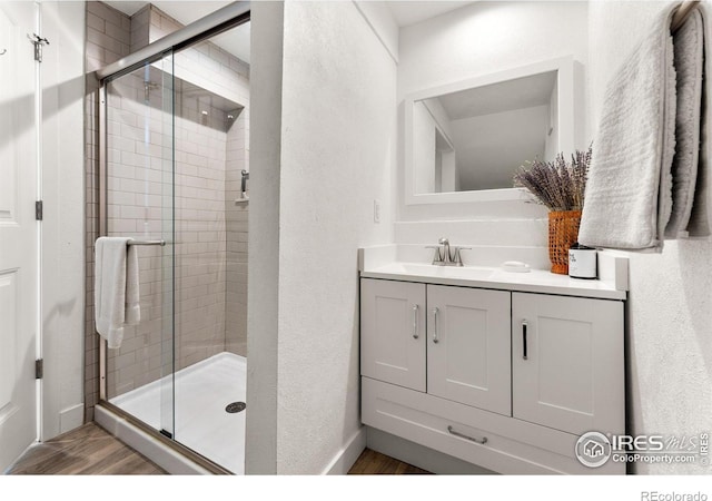 bathroom with vanity, an enclosed shower, and wood-type flooring