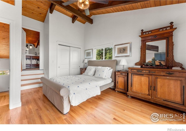 bedroom with light wood-style floors, wooden ceiling, a closet, and lofted ceiling with beams