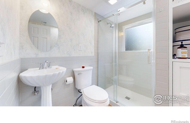 bathroom featuring walk in shower, toilet, and tile walls