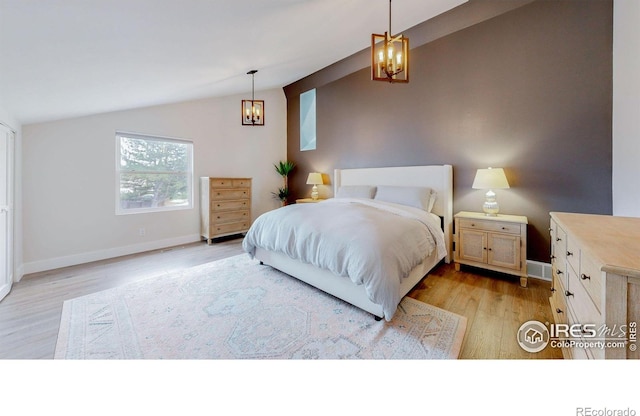 bedroom featuring light hardwood / wood-style flooring, lofted ceiling, and a notable chandelier