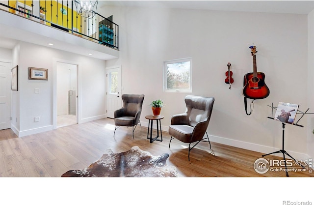 sitting room with light hardwood / wood-style floors and high vaulted ceiling