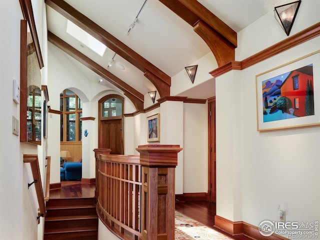 staircase featuring wood-type flooring, vaulted ceiling, and track lighting
