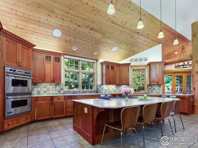 kitchen featuring vaulted ceiling, wood ceiling, stainless steel appliances, and a kitchen island