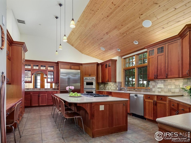 kitchen featuring appliances with stainless steel finishes, a kitchen island, decorative backsplash, hanging light fixtures, and wooden ceiling