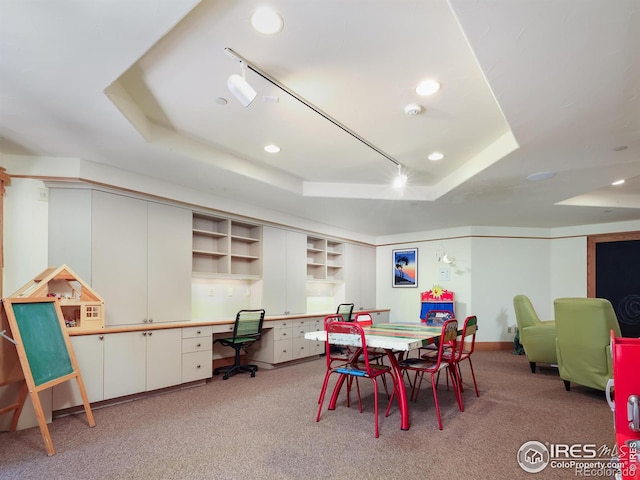 dining space featuring built in desk, carpet, and a tray ceiling