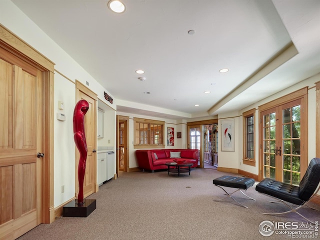 living room featuring a raised ceiling, french doors, and carpet flooring