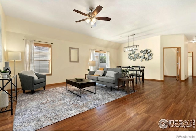 living room with vaulted ceiling, ceiling fan with notable chandelier, and dark hardwood / wood-style flooring