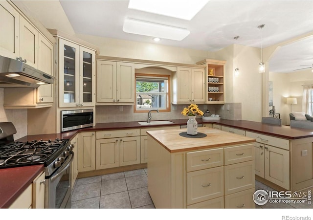 kitchen featuring butcher block countertops, sink, a center island, stainless steel appliances, and cream cabinets