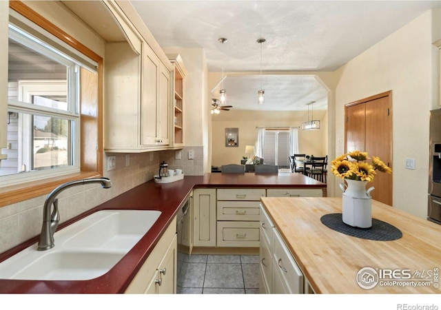 kitchen featuring butcher block countertops, decorative light fixtures, sink, decorative backsplash, and stainless steel dishwasher