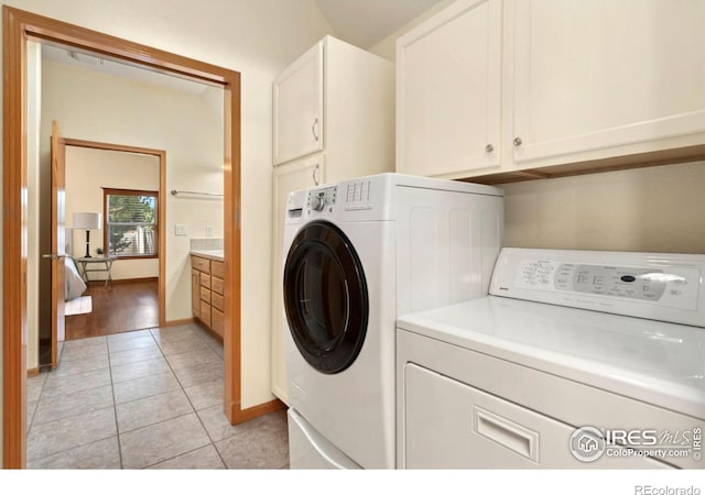 laundry area with separate washer and dryer, cabinets, and light tile patterned flooring