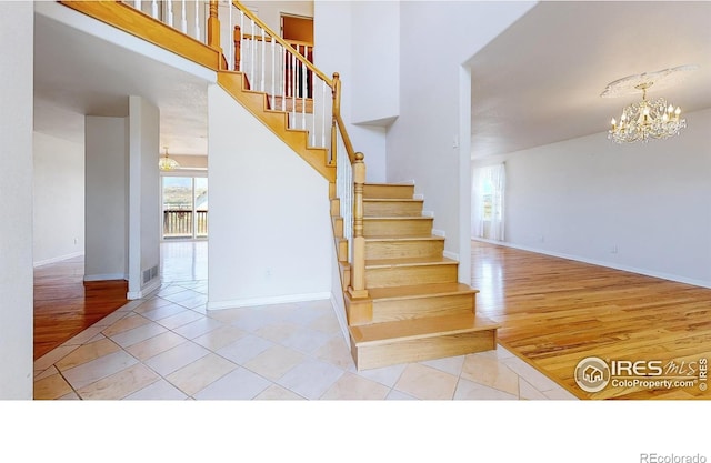 stairs with tile patterned flooring and an inviting chandelier