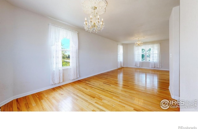 unfurnished room featuring wood-type flooring and an inviting chandelier