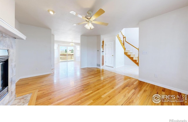 unfurnished living room with a high end fireplace, light hardwood / wood-style flooring, and ceiling fan