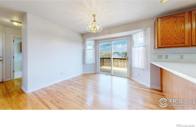 unfurnished dining area featuring a notable chandelier and light wood-type flooring