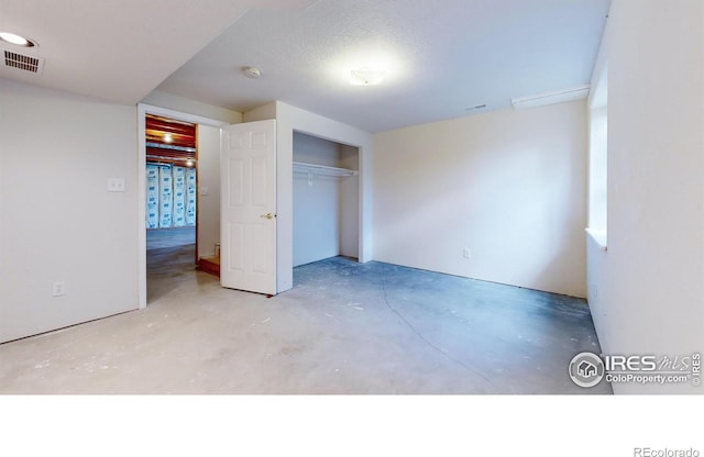 unfurnished bedroom featuring a textured ceiling and a closet