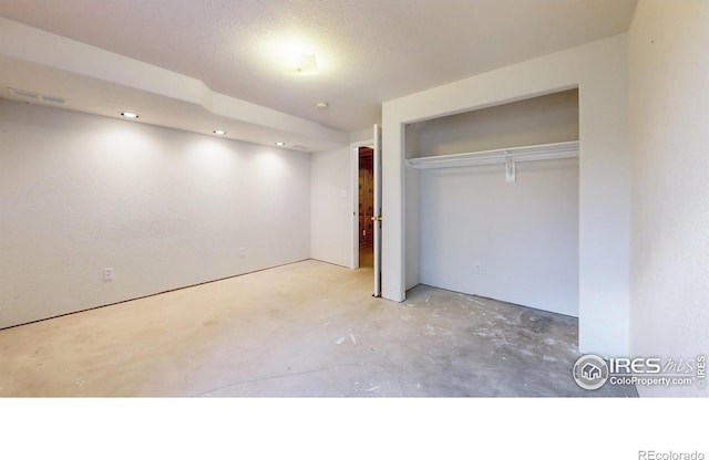 unfurnished bedroom featuring concrete floors, a textured ceiling, and a closet