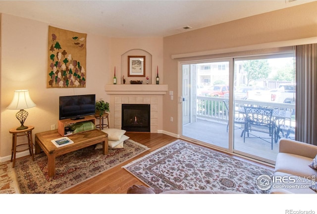 living room featuring a tiled fireplace and hardwood / wood-style flooring