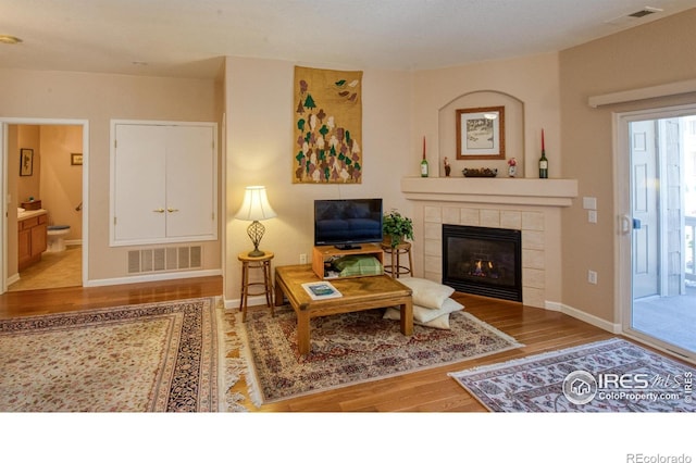 living room featuring a tile fireplace and light hardwood / wood-style floors