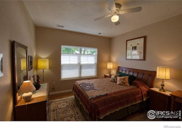 bedroom featuring hardwood / wood-style floors, a textured ceiling, and ceiling fan