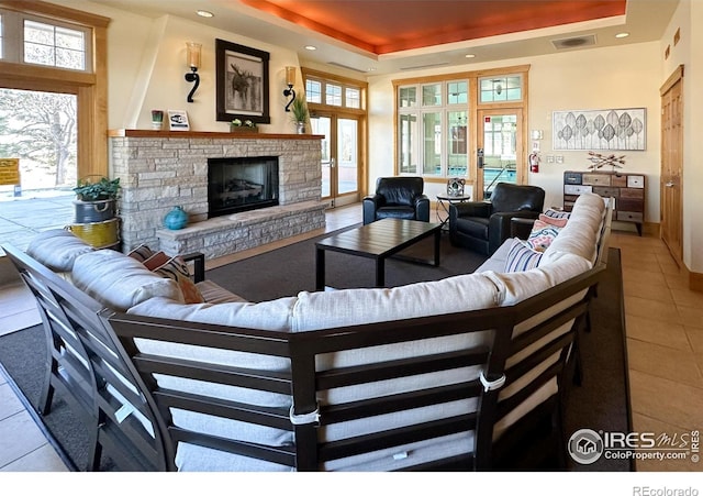 tiled living room with french doors, a fireplace, and a tray ceiling