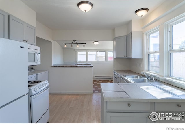 kitchen with gray cabinetry, sink, a baseboard heating unit, white appliances, and washer and dryer