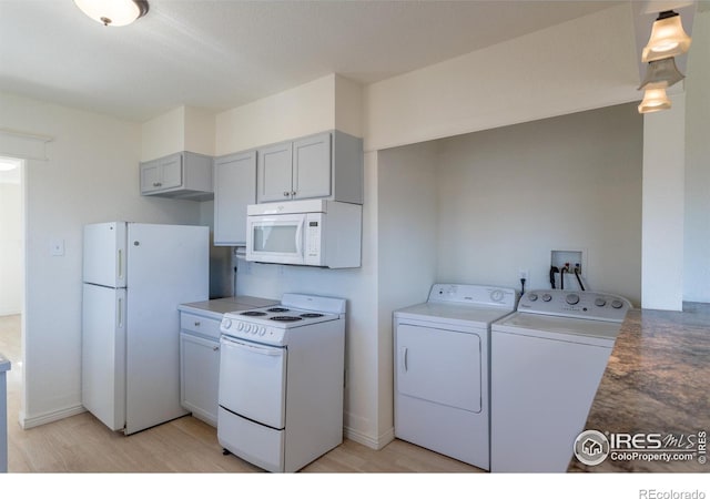 kitchen with gray cabinets, washer and clothes dryer, white appliances, and light hardwood / wood-style flooring