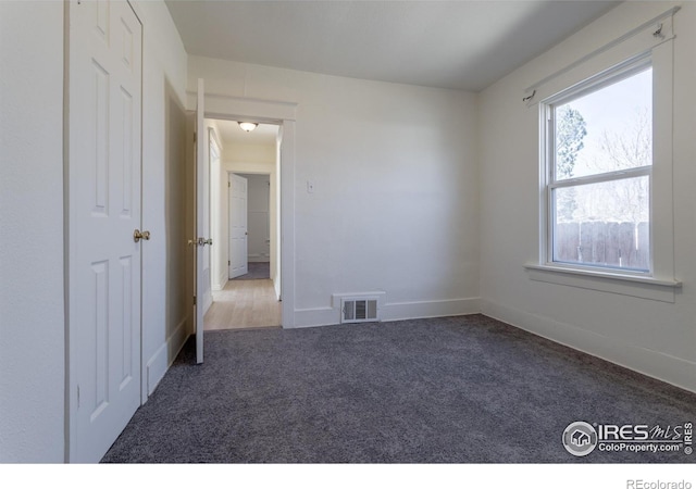 spare room with dark carpet