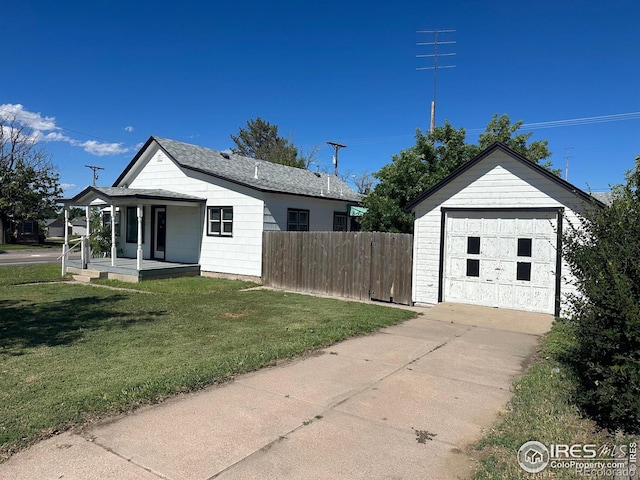 view of front of house featuring an outbuilding, a front lawn, covered porch, and a garage