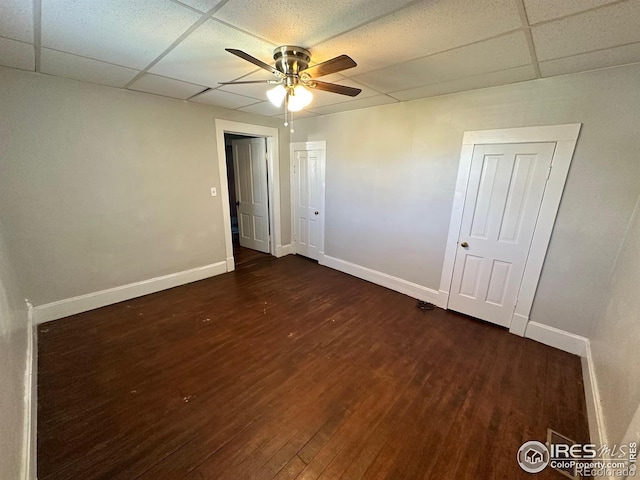 empty room featuring dark hardwood / wood-style flooring, a drop ceiling, and ceiling fan