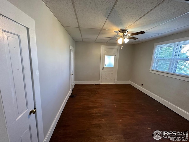 spare room with a paneled ceiling, ceiling fan, and dark hardwood / wood-style flooring