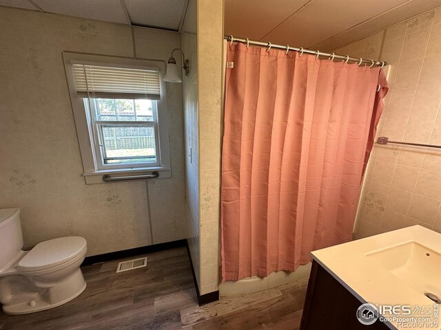 bathroom with hardwood / wood-style flooring, vanity, toilet, and tile walls