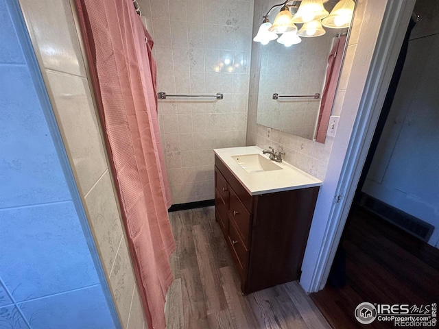 bathroom featuring a shower with shower curtain, backsplash, vanity, hardwood / wood-style flooring, and an inviting chandelier