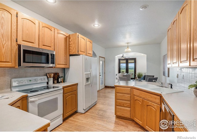 kitchen with backsplash, sink, hanging light fixtures, and white appliances