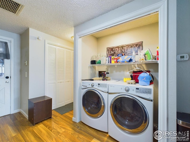 laundry area with visible vents, a textured ceiling, separate washer and dryer, wood finished floors, and laundry area