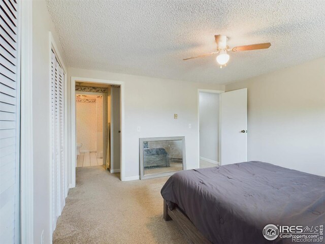 bedroom with baseboards, a ceiling fan, light colored carpet, a textured ceiling, and a fireplace