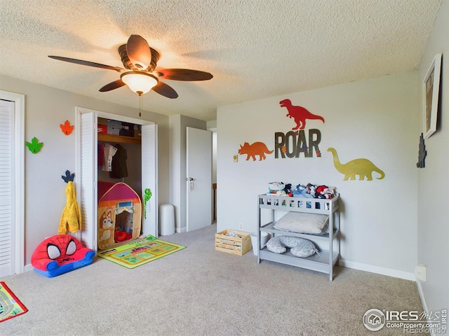 game room featuring a textured ceiling, carpet floors, a ceiling fan, and baseboards