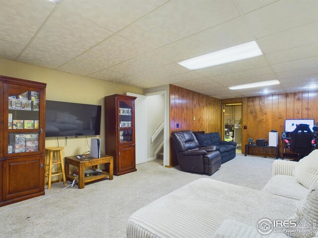 living room featuring wood walls, light colored carpet, and a paneled ceiling